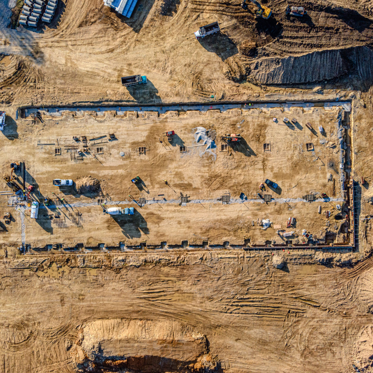 An aerial view of a large agricultural field in the process of being cultivated by a tractor